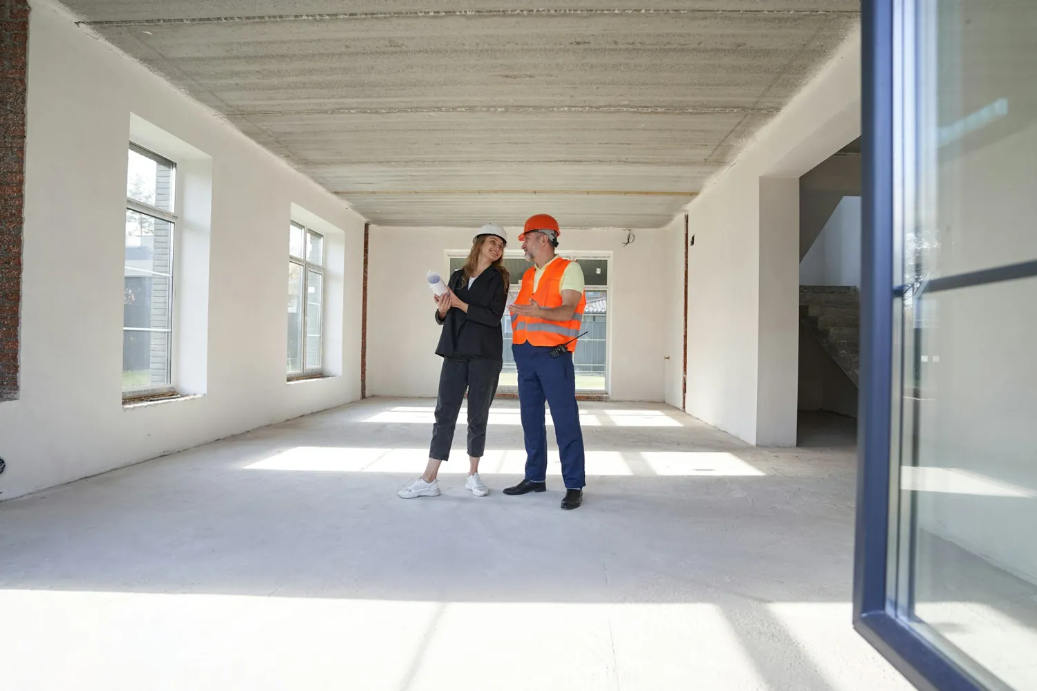 Engenheira da OMNIA conversando com profissional dentro de obra residencial
