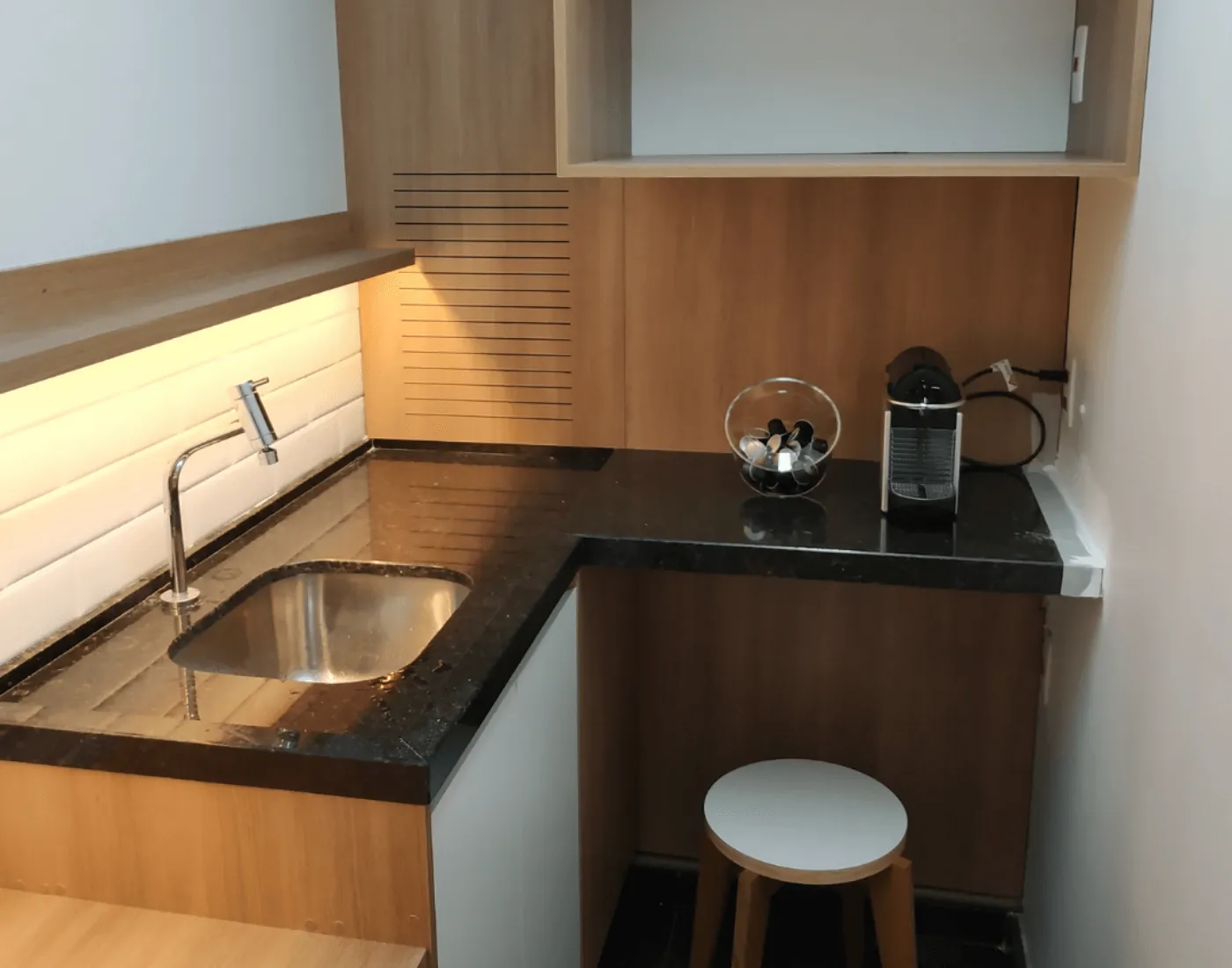 Cozinha com bancada de granito preto em apartamento reformado em Pinheiros