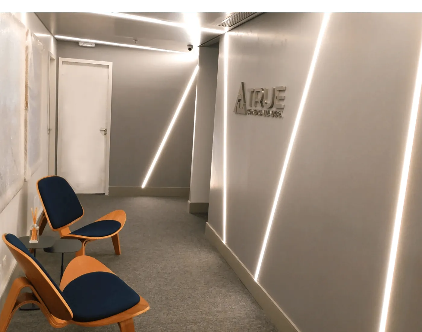 Recepção do escritório da True Comercializadora com iluminação em fitas de LED